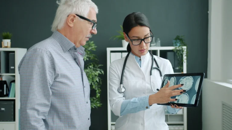 Médecin montrant une imagerie médicale sur tablette à un homme âgé lors d'une consultation