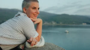 Portrait d'une femme aux cheveux rasés souriant sereinement en regardant vers l'horizon