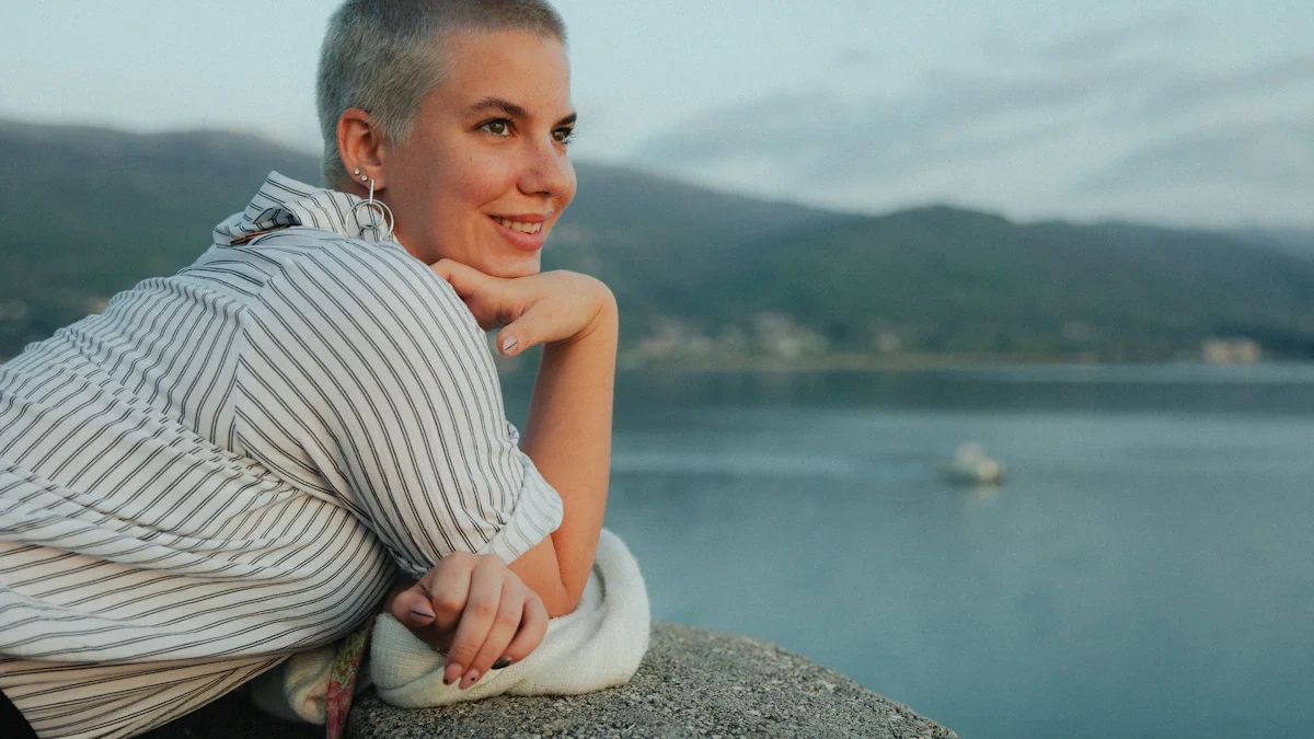 Portrait d'une femme aux cheveux rasés souriant sereinement en regardant vers l'horizon