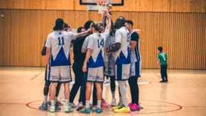 Une équipe de basketball du CEST de Tours réunie en cercle au milieu du terrain, symbolisant la cohésion et l'esprit de famille du club.