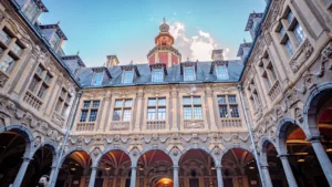 Visiteurs dans la cour intérieure majestueuse de la Vieille Bourse à Lille sous un ciel bleu