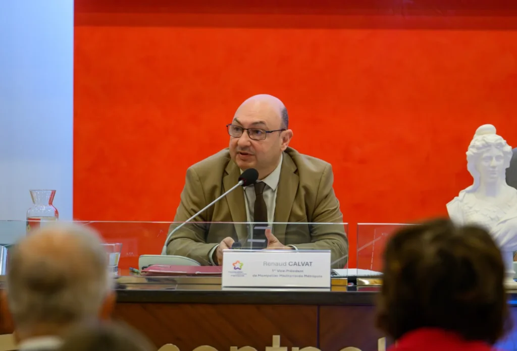 Renaud Calvat s'exprime au micro lors d'une conférence de presse devant un fond rouge.
