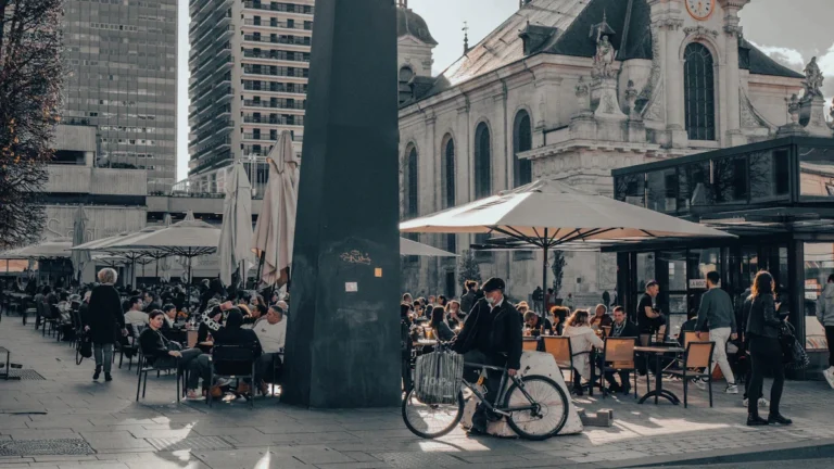 Personnes profitant des terrasses sur une place piétonne animée avec une église historique en arrière-plan à Nancy.