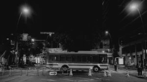 Un bus de ville circulant de nuit à côté de barrières de signalisation de chantier urbain