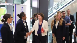 Une femme en veste blanche serre la main d'une autre femme en uniforme bleu marine.
