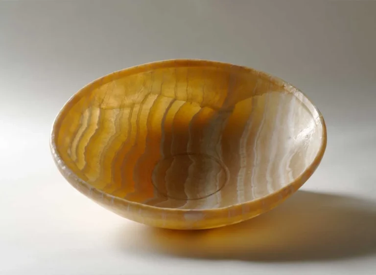 Bol ancien en pierre jaune translucide présentant de multiples bandes ondulées naturelles.