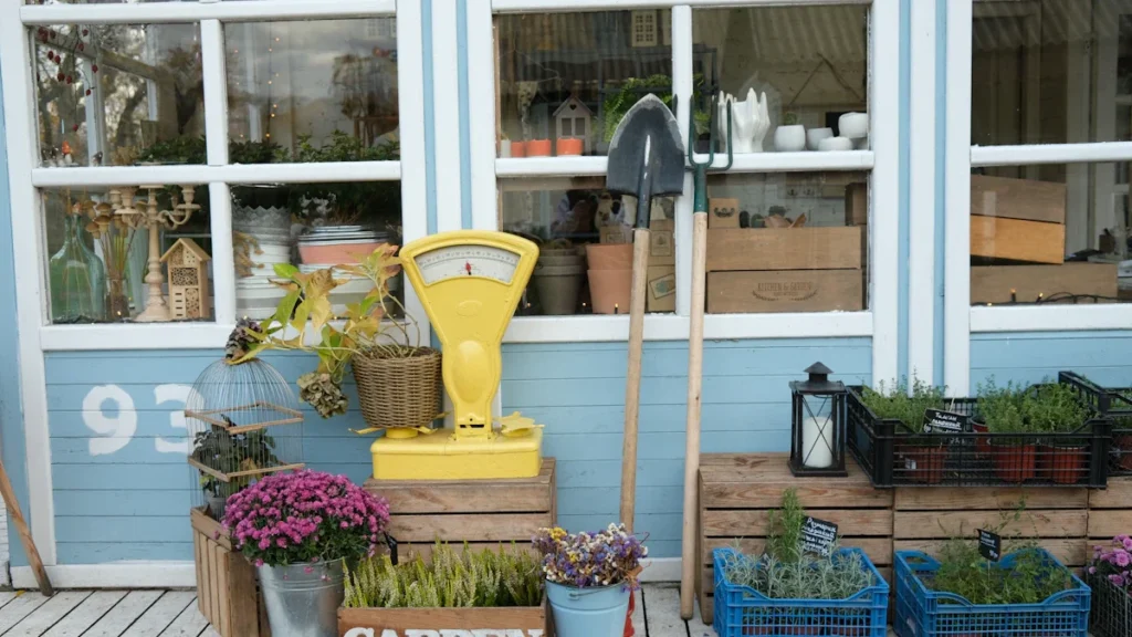 Façade colorée avec fleurs, outils de jardinage et caisses en bois pour un jardin urbain.
