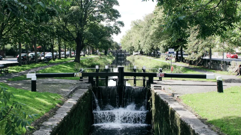 Vue d'un canal calme entouré d'arbres verdoyants avec une petite écluse.