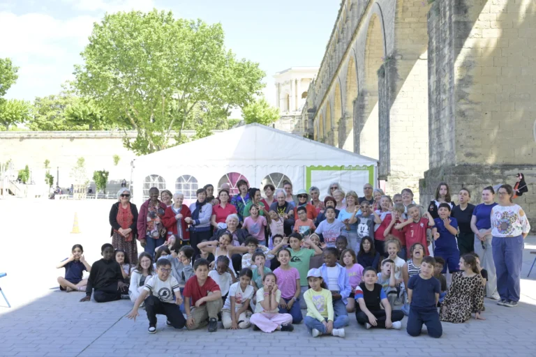 Un grand groupe d'enfants et d'adultes faisant des grimaces devant un ancien aqueduc en pierre.