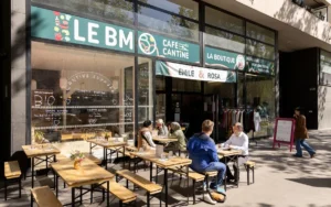 Des clients déjeunent en terrasse devant la façade vitrée du café cantine solidaire Le BM.