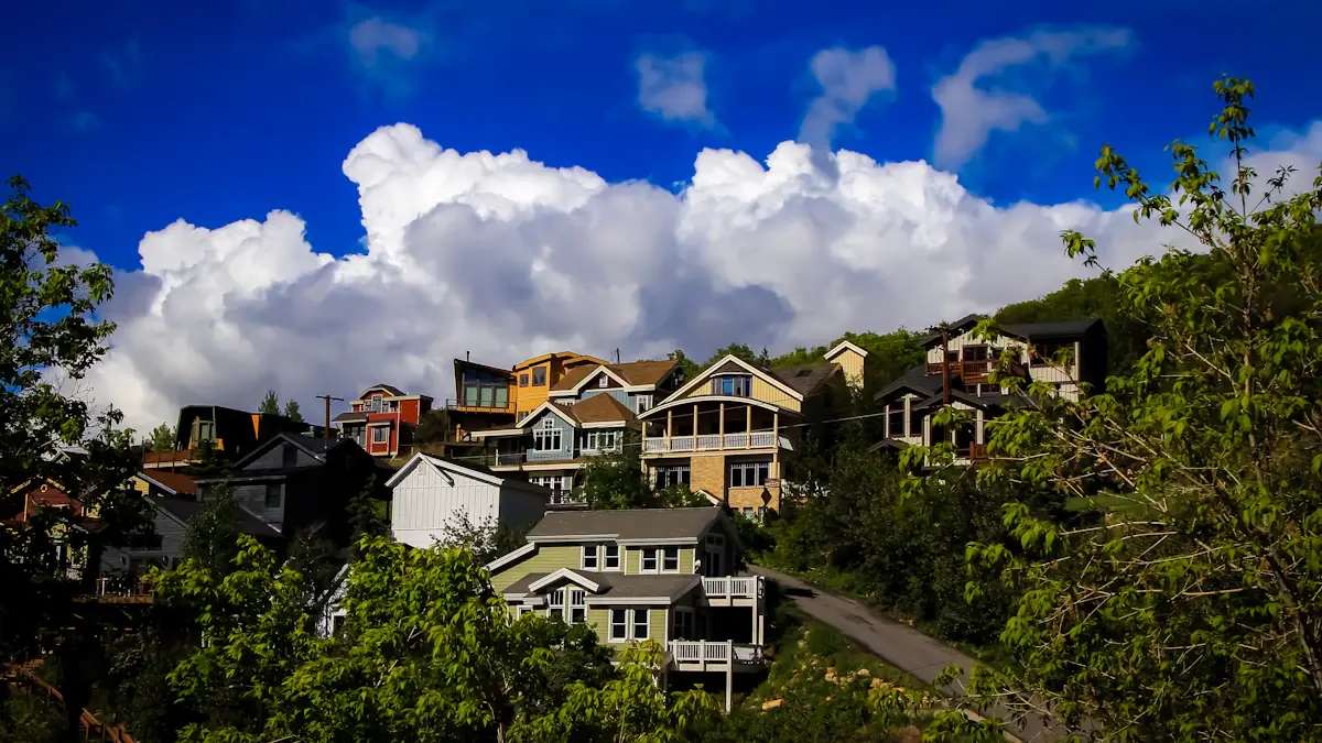 Maisons résidentielles en bordure de colline avec un ciel bleu et des nuages.