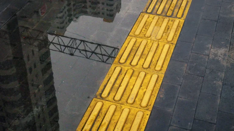 Dalle podotactile jaune sur un trottoir urbain pour faciliter l'autonomie des personnes malvoyantes.