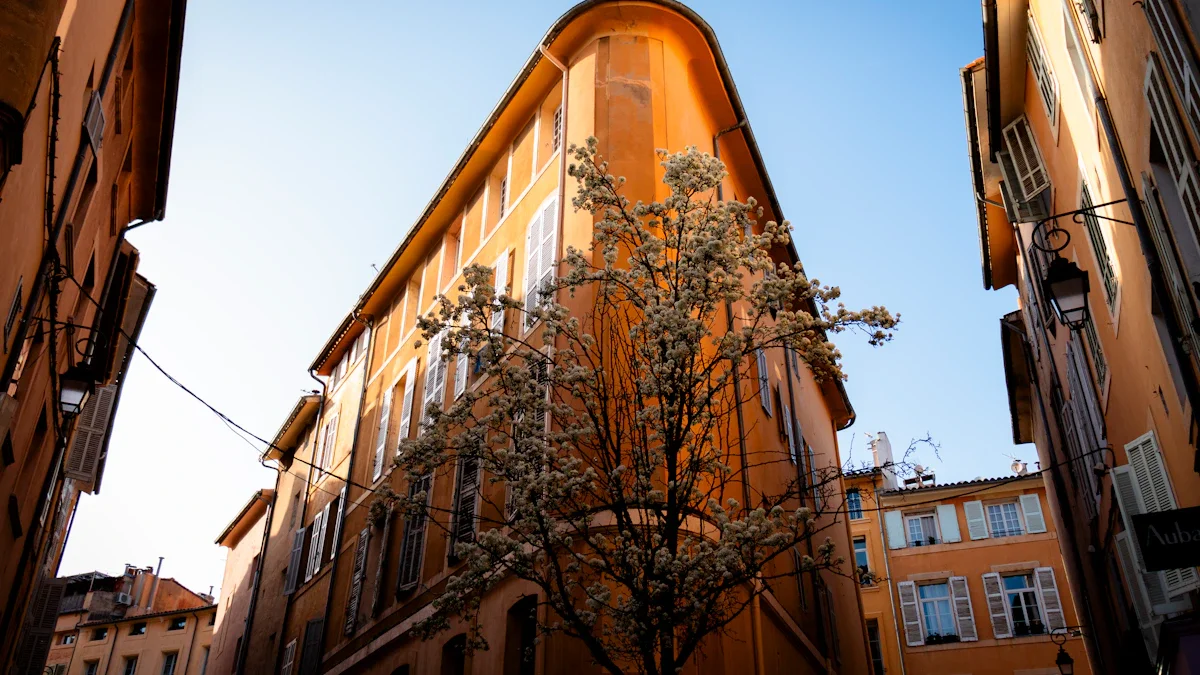 Immeuble d'angle aux façades ocre typiques d'Aix-en-Provence avec un arbre en fleurs sous un ciel bleu.