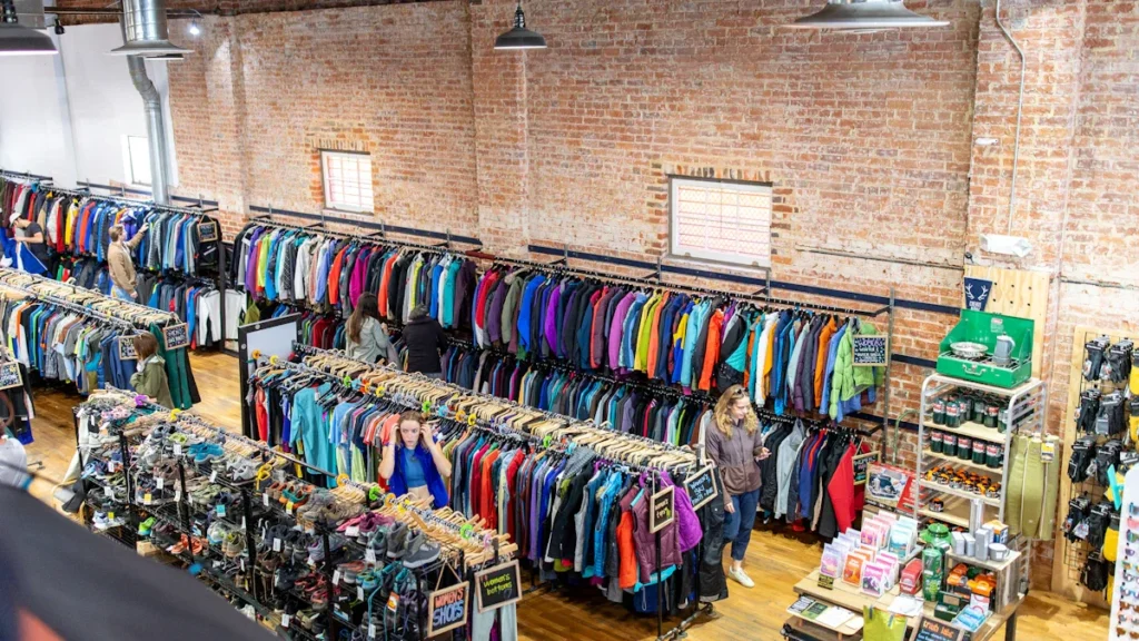 Intérieur d'une ressourcerie à Aix-en-Provence montrant des rayons de vêtements et d'articles de seconde main.