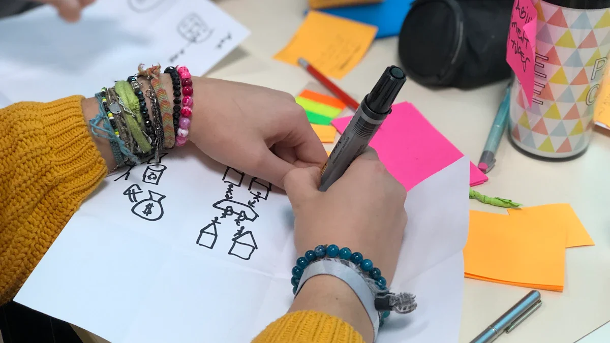 Gros plan sur les mains d'un habitant dessinant des projets de transformation urbaine lors d'un atelier citoyen à Amiens.