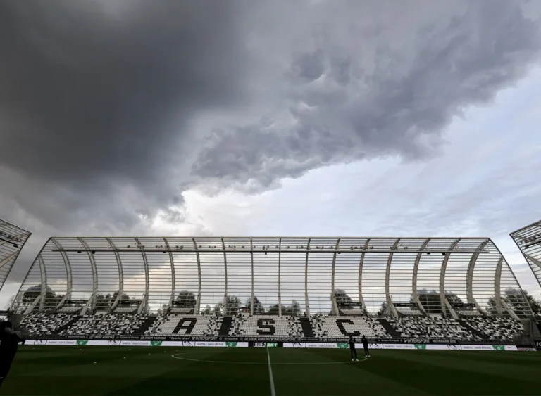 Vue d'un stade de football sous un ciel d'orage menaçant avec des gradins vides.