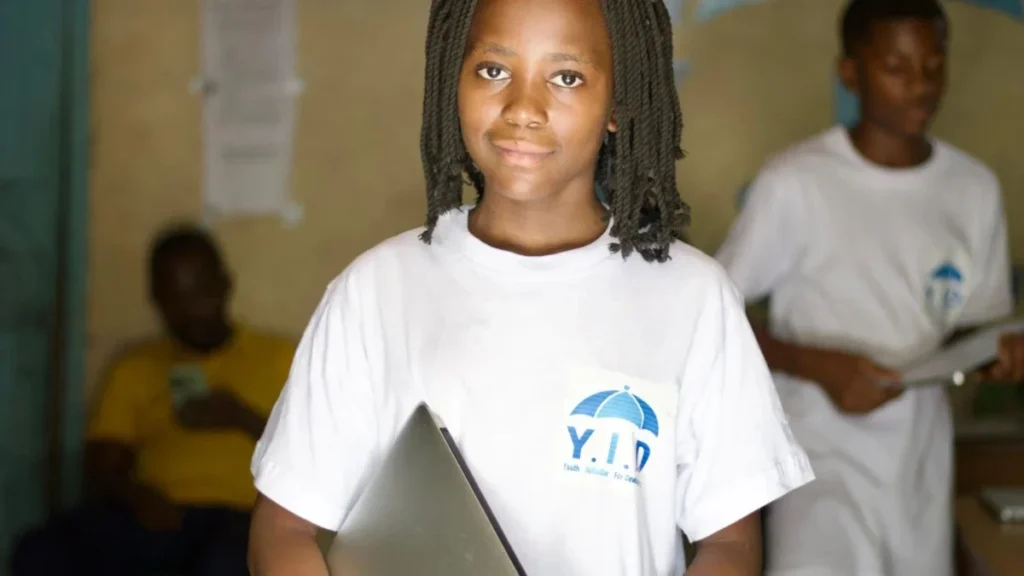 Une jeune femme souriante tenant un ordinateur portable dans une salle de formation à Saint-Paul.