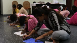 Plusieurs jeunes participants assis par terre lors d'un atelier d'écriture et de création littéraire à Perpignan.