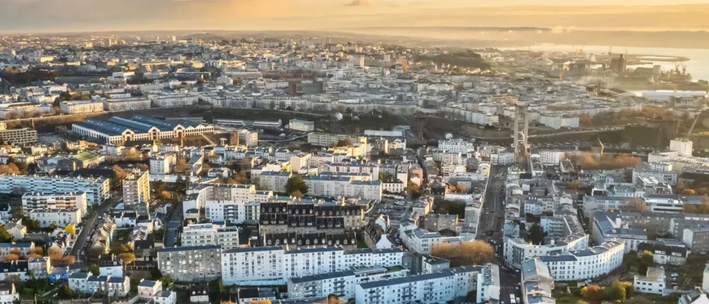 Vue aérienne panoramique d'une ville française côtière baignée par la lumière dorée du soleil couchant.