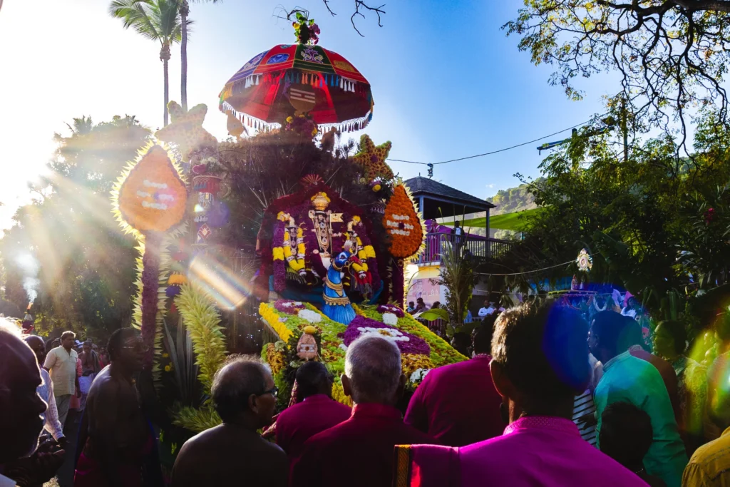 Un char religieux hindou richement orné de fleurs et de plumes de paon lors d'une procession.