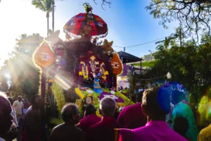 Un char religieux hindou richement orné de fleurs et de plumes de paon lors d'une procession.