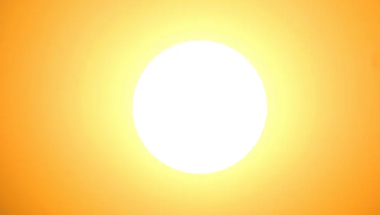 Un grand soleil blanc circulaire centré dans un ciel dégradé de jaune et d'orange vif.