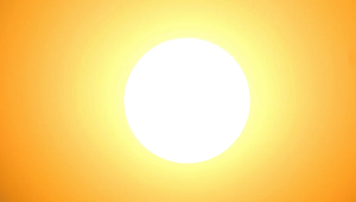 Un grand soleil blanc circulaire centré dans un ciel dégradé de jaune et d'orange vif.