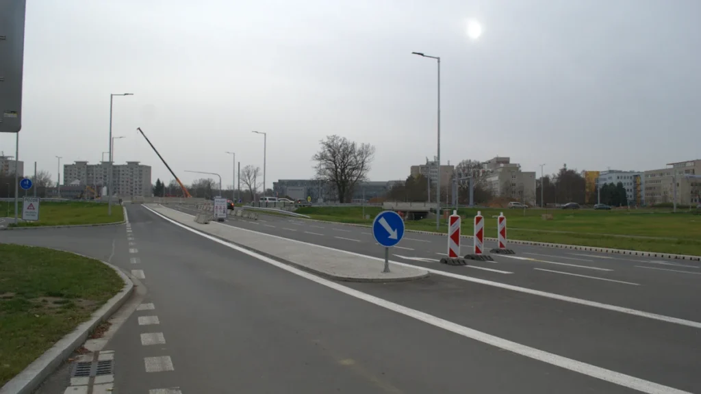 Panneau de signalisation bleu avec flèche blanche et cônes de chantier marquant un changement de voie.