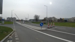 Panneau de signalisation bleu avec flèche blanche et cônes de chantier marquant un changement de voie.