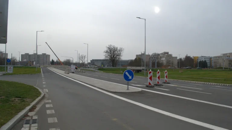Panneau de signalisation bleu avec flèche blanche et cônes de chantier marquant un changement de voie.