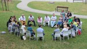 Un groupe de citoyens réunis en cercle dans un parc pour discuter de projets locaux et du budget participatif.