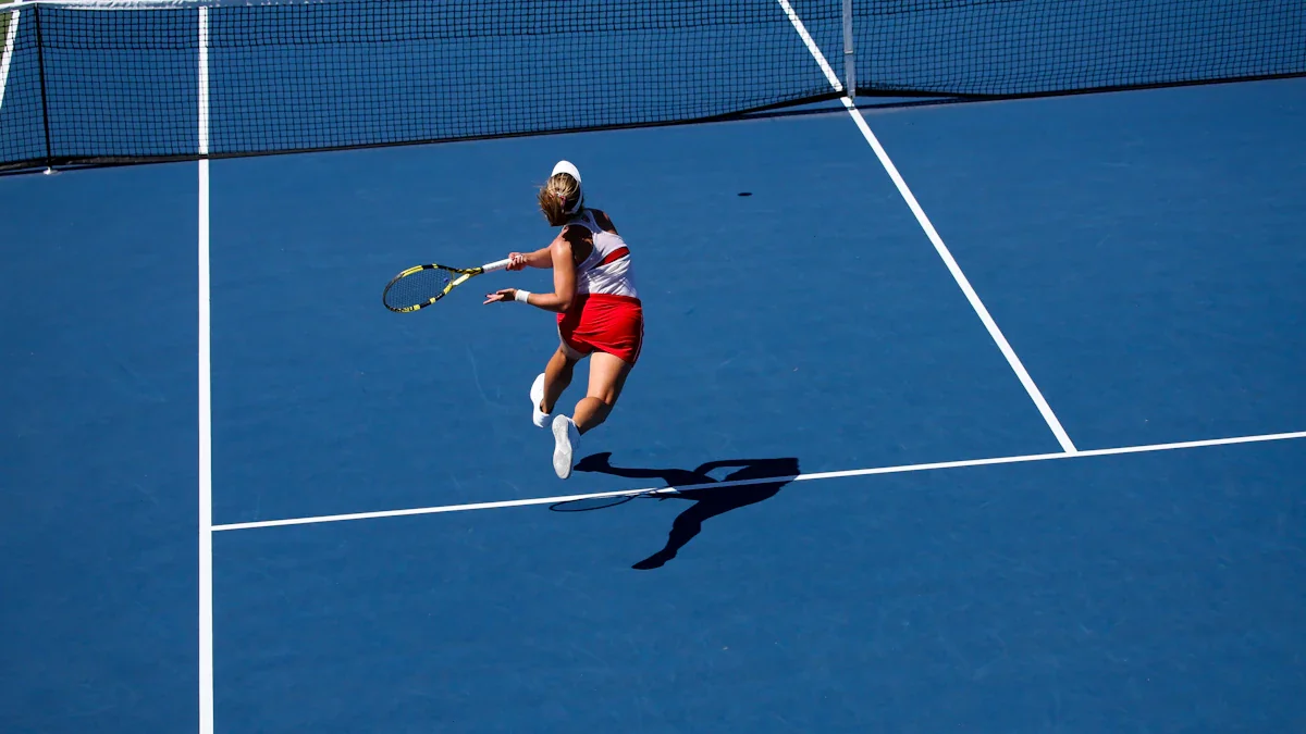 Une joueuse de tennis en pleine action sur un court dur bleu extérieur.