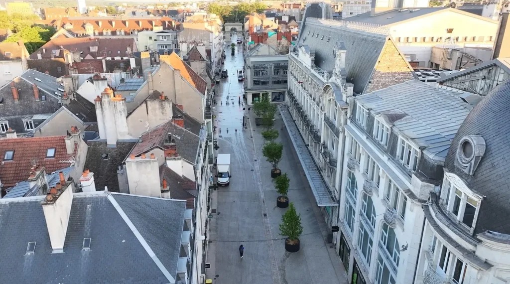 Vue aérienne d'une rue piétonne pavée bordée de bâtiments historiques et d'arbres en pots.