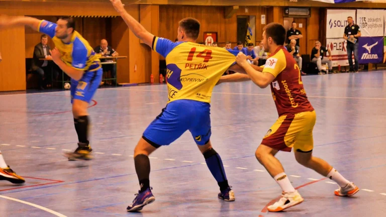 Joueurs de handball en pleine action physique lors d'un match de compétition en intérieur.
