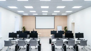 Vue d'ensemble d'une salle informatique scolaire avec des rangées d'ordinateurs et un écran de projection.