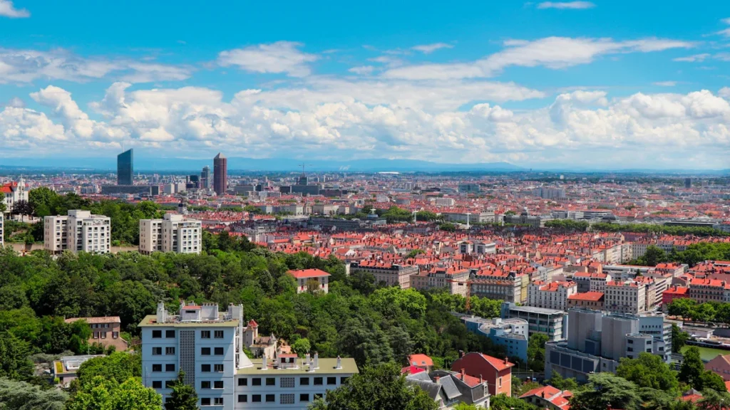 Vue panoramique aérienne de Lyon mettant en avant les tours de la Part-Dieu et le tissu urbain.