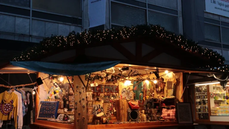 Un chalet en bois typique d'un marché de Noël, illuminé et rempli d'objets artisanaux à la nuit tombée.