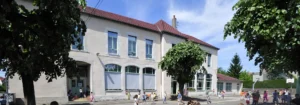 Enfants jouant dans la cour d'une école primaire traditionnelle sous un soleil radieux.