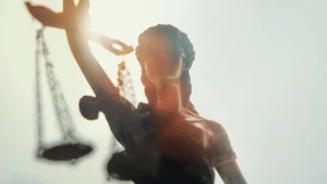 Statue de la Justice aux yeux bandés tenant une balance sous un soleil éclatant.