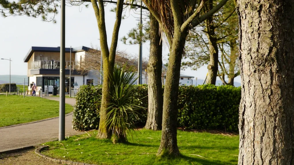 Une allée piétonne et un bâtiment moderne entourés de verdure dans un parc public.