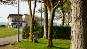 Une allée piétonne et un bâtiment moderne entourés de verdure dans un parc public.