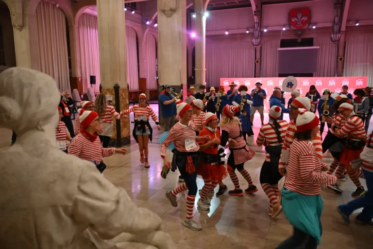 Groupe de personnes déguisées en Charlie avec hauts rayés rouge et blanc dans une grande salle.