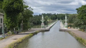 Le pont-canal de Briare avec ses colonnes ornementales traversant la Loire sous un ciel nuageux.