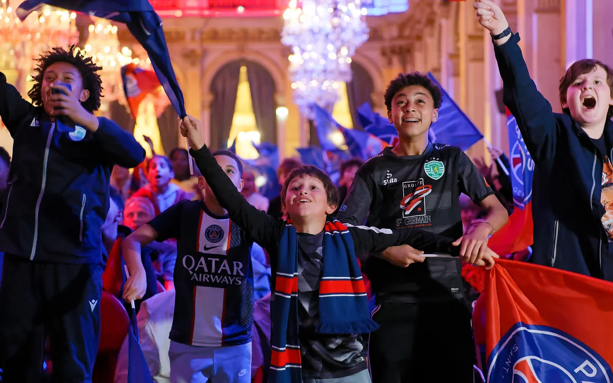 Des jeunes supporters en maillots de football célèbrent avec enthousiasme dans une grande salle de réception.