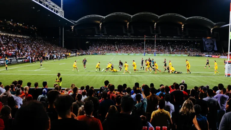 Un grand stade de football français illuminé de nuit lors d'un match caritatif devant une foule nombreuse.