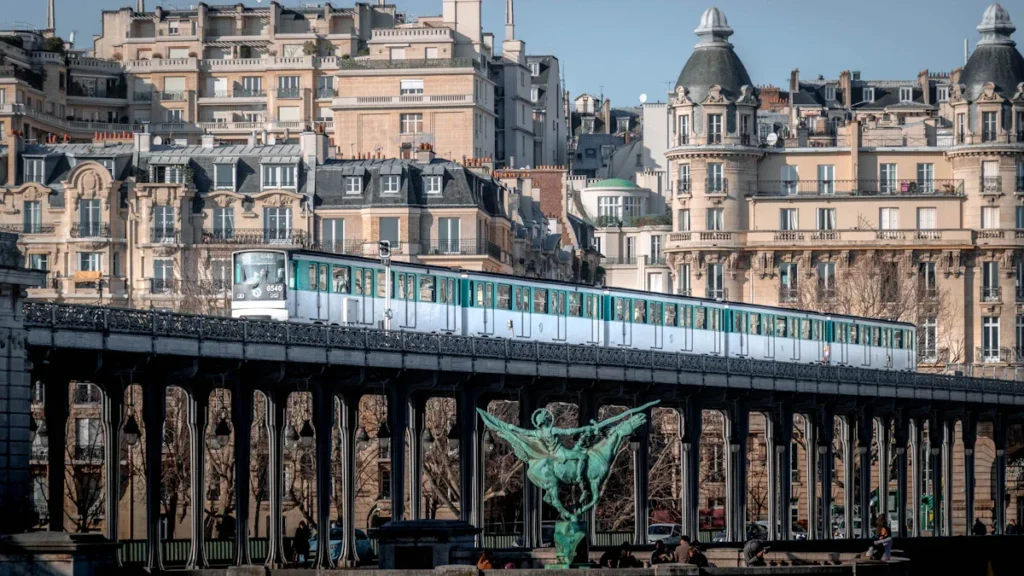 Un train du métro parisien circulant sur un viaduc devant des immeubles de style haussmannien.