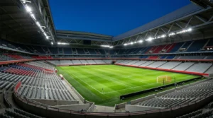 Grand stade de football vide illuminé par des projecteurs sous un ciel nocturne dégagé.
