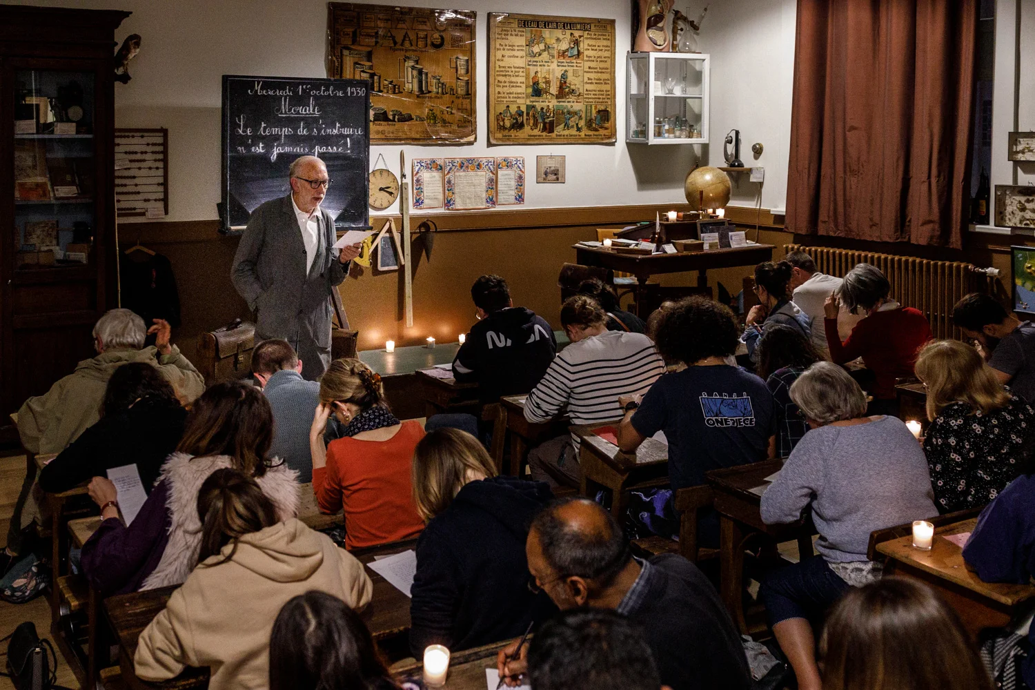 Un enseignant âgé devant un tableau noir s'adresse à des adultes dans une classe rétro.