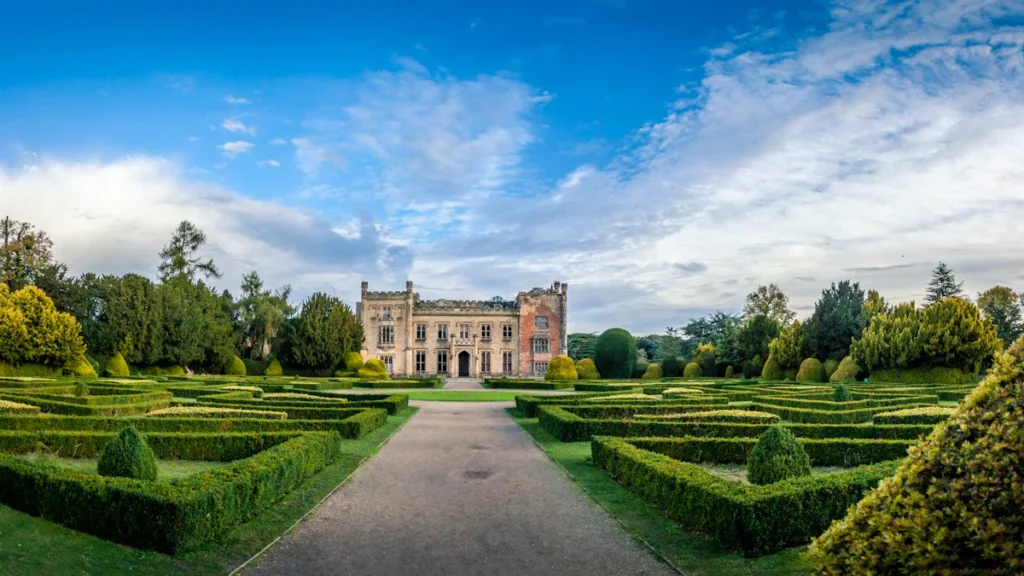 Vue panoramique d'un château entouré de jardins à la française et de vastes espaces verts.