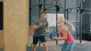 Un entraîneur sportif conseille une athlète lors d'un exercice, illustrant le concept de formation dans le sport.